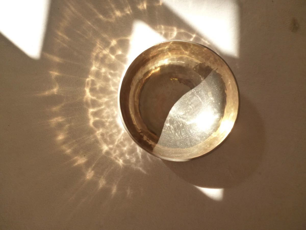 singing bowl casting light patterns on a warm wall